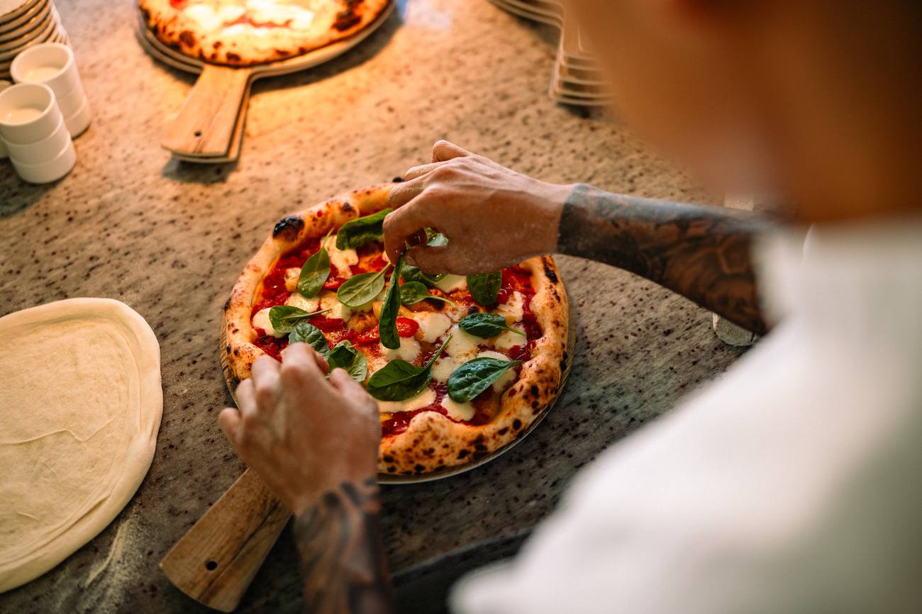Chef finishing a pizza with basil