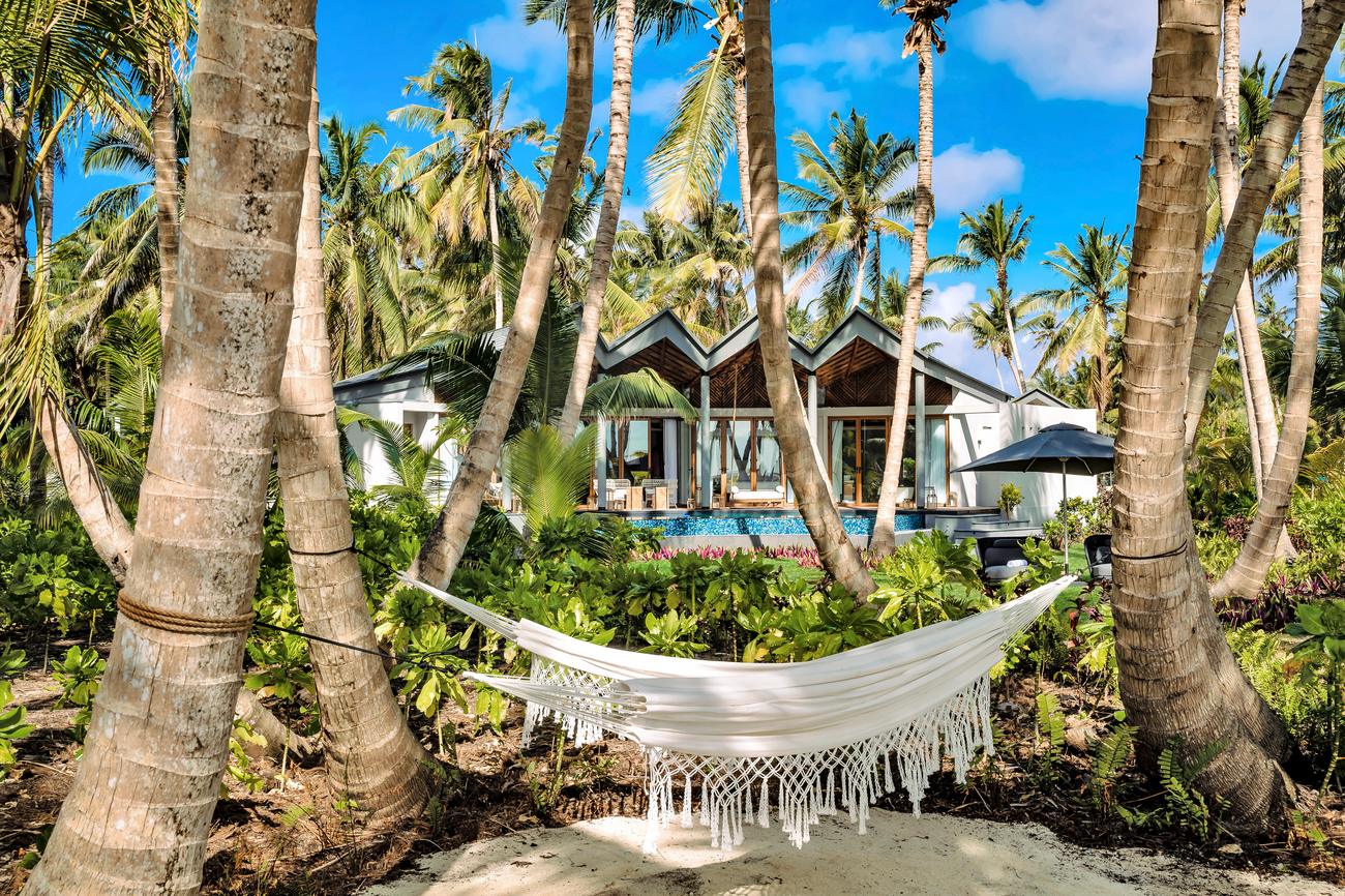Hammock between palms in front of a villa